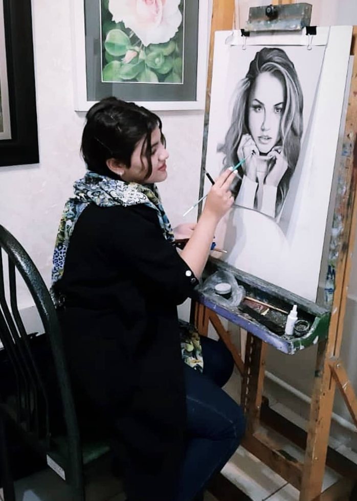 Ghazaleh at her easel, working on a charcoal portrait